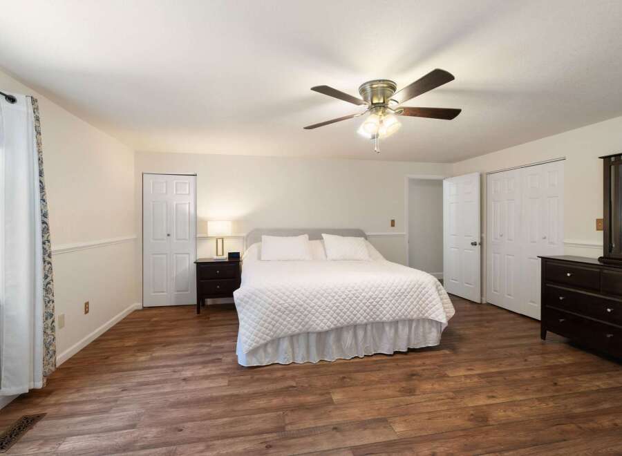 This spacious bedroom features a comfortable king-sized bed with a white quilted comforter, perfect for relaxation.