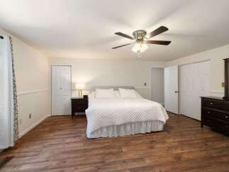 This spacious bedroom features a comfortable king-sized bed with a white quilted comforter, perfect for relaxation.