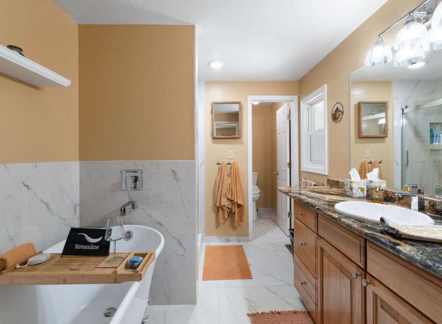 Indulge in relaxation in this luxurious bathroom featuring a freestanding soaking tub with a convenient bath tray, perfect for unwinding.