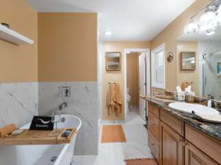 Indulge in relaxation in this luxurious bathroom featuring a freestanding soaking tub with a convenient bath tray, perfect for unwinding.
