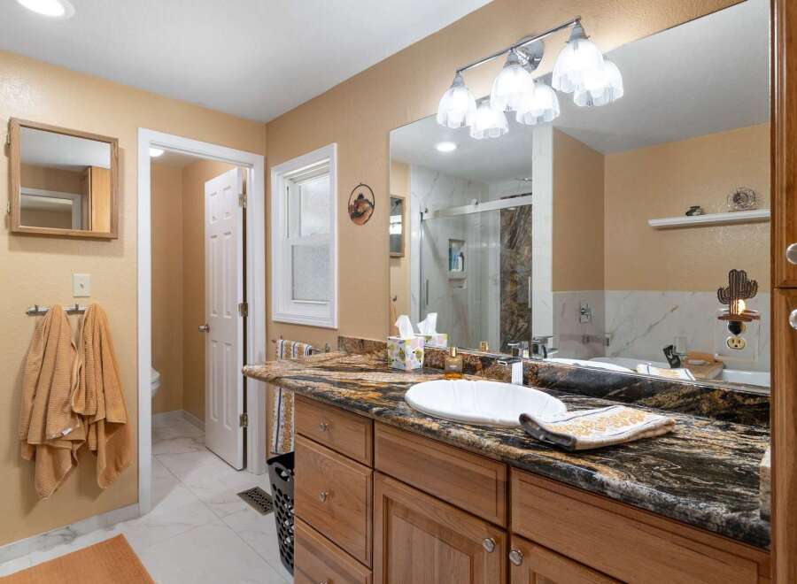 Step into this beautifully updated bathroom featuring a spacious vanity with a granite countertop and a large undermount sink.
