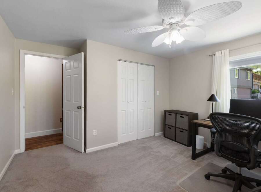 This bedroom offers a functional workspace with a desk, ergonomic chair, and computer, perfect for remote work or study.