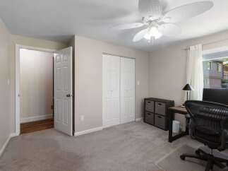 This bedroom offers a functional workspace with a desk, ergonomic chair, and computer, perfect for remote work or study.