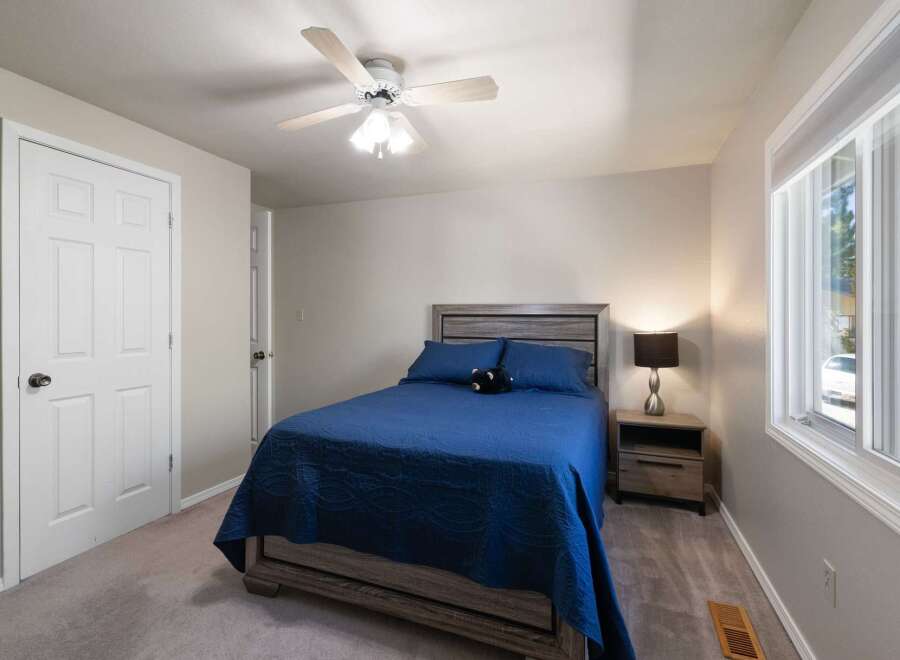 Discover comfort and style in this inviting bedroom, featuring a plush blue bedspread and a modern gray wood headboard.