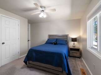 Discover comfort and style in this inviting bedroom, featuring a plush blue bedspread and a modern gray wood headboard.