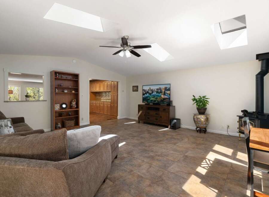 This spacious living area boasts vaulted ceilings with multiple skylights, flooding the room with natural light.