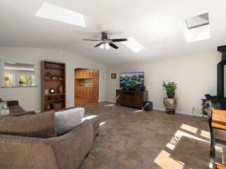 This spacious living area boasts vaulted ceilings with multiple skylights, flooding the room with natural light.