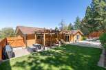 Enjoy outdoor living with this charming backyard featuring a spacious wooden pergola perfect for al fresco dining and relaxation.