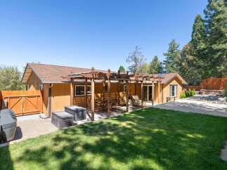 Enjoy outdoor living with this charming backyard featuring a spacious wooden pergola perfect for al fresco dining and relaxation.