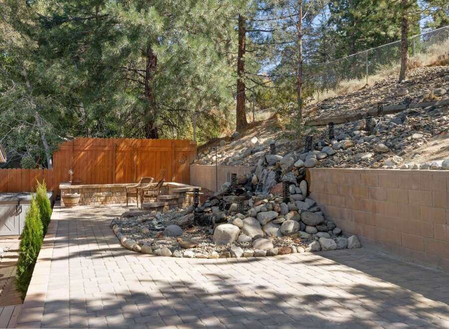 Escape to your private backyard oasis featuring a stunning multi-tiered waterfall and spa.