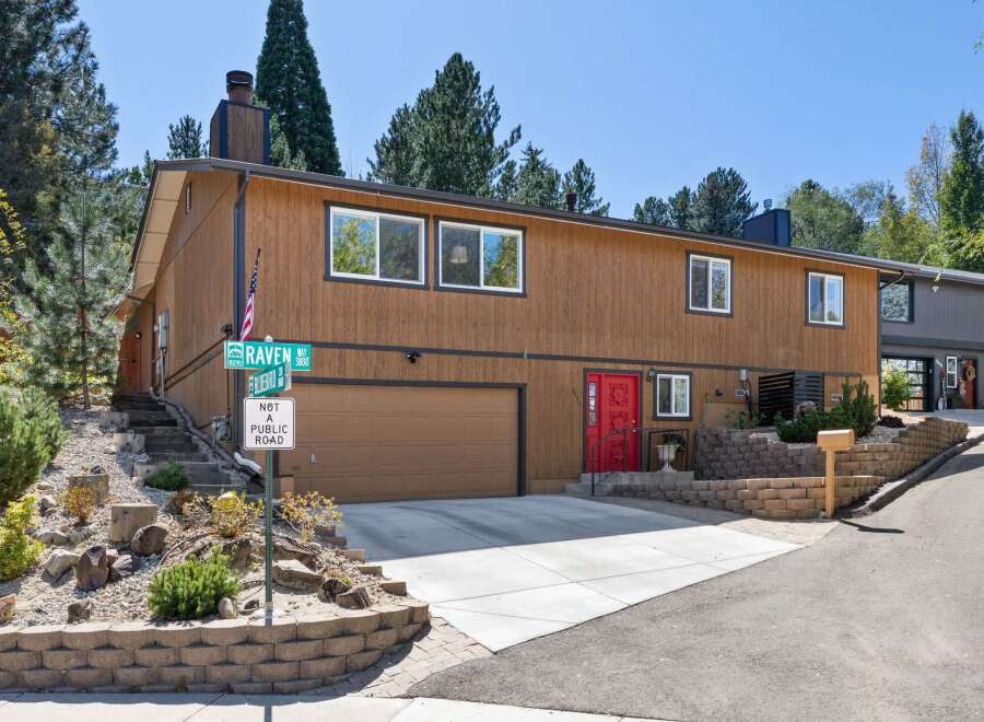 Discover this charming multi-level home featuring a warm brown wood exterior and a striking red front door.