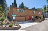 Discover this charming multi-level home featuring a warm brown wood exterior and a striking red front door.