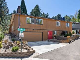 Discover this charming multi-level home featuring a warm brown wood exterior and a striking red front door.