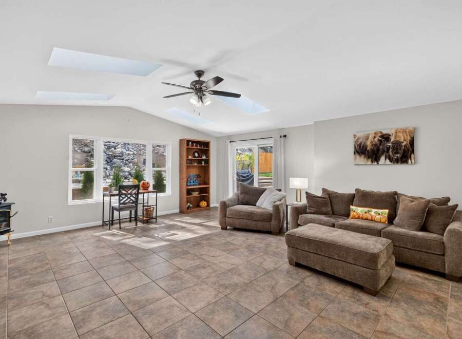 This spacious living room features a vaulted ceiling with skylights, flooding the space with natural light.
