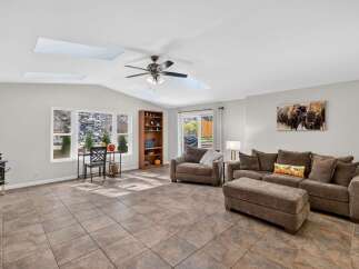 This spacious living room features a vaulted ceiling with skylights, flooding the space with natural light.