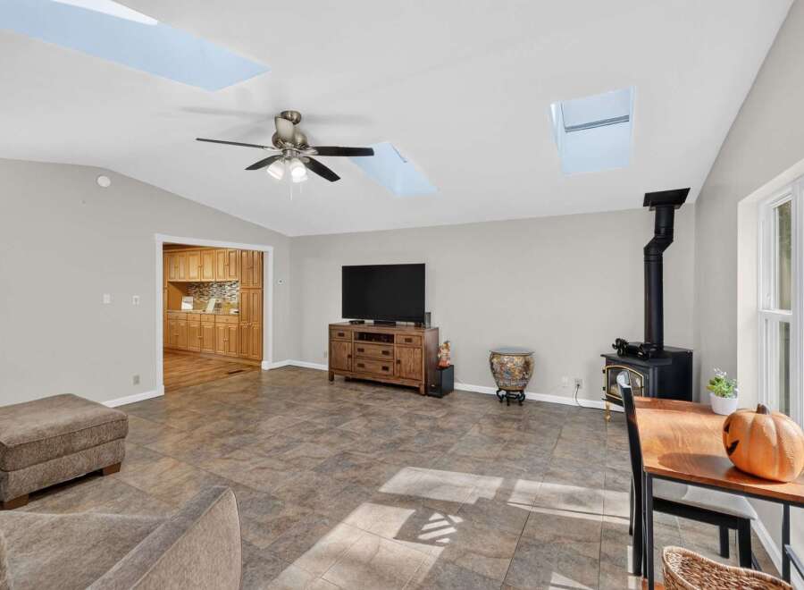 This spacious living area boasts a modern entertainment setup with a large flat-screen TV mounted above a wooden media console.