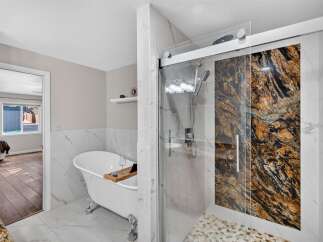 Experience luxury in this stunning bathroom featuring a freestanding clawfoot tub and a spacious walk-in shower with a dramatic granite accent wall.