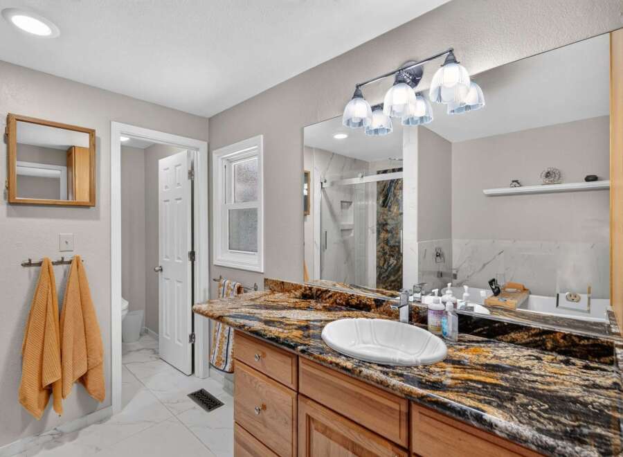 This stunning bathroom boasts a luxurious granite countertop with an undermount sink, complemented by a sleek chrome faucet.