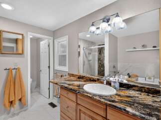 This stunning bathroom boasts a luxurious granite countertop with an undermount sink, complemented by a sleek chrome faucet.