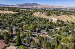 Discover this stunning aerial view of a suburban neighborhood nestled against rolling hills and a majestic mountain backdrop.