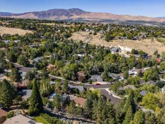 Discover this stunning aerial view of a suburban neighborhood nestled against rolling hills and a majestic mountain backdrop.