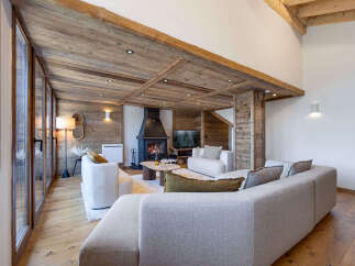 Experience rustic luxury in this stunning living room, featuring a grand fireplace and exposed wooden beams that create a warm, inviting atmosphere.