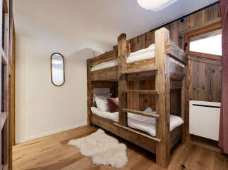 This charming bedroom features a rustic wooden bunk bed, perfect for accommodating guests or family.