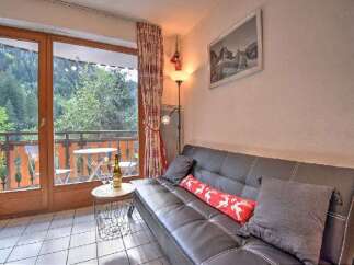 Enjoy the stunning mountain views from this cozy living area, featuring a comfortable sofa and direct access to a private balcony.