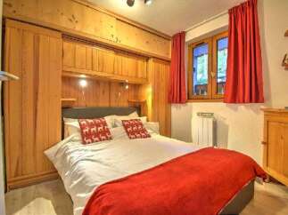 Experience cozy mountain living in this charming bedroom featuring a comfortable bed adorned with festive reindeer pillows and a warm red throw.
