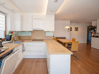 This modern kitchen features sleek white cabinetry and a light wood countertop, offering a bright and airy feel.