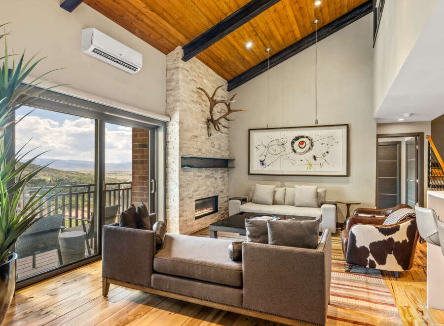 Experience luxurious mountain living in this stunning great room, featuring a soaring vaulted wood-beamed ceiling and a striking stone fireplace.