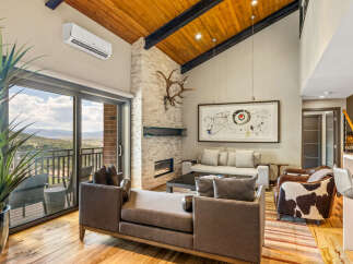 Experience luxurious mountain living in this stunning great room, featuring a soaring vaulted wood-beamed ceiling and a striking stone fireplace.