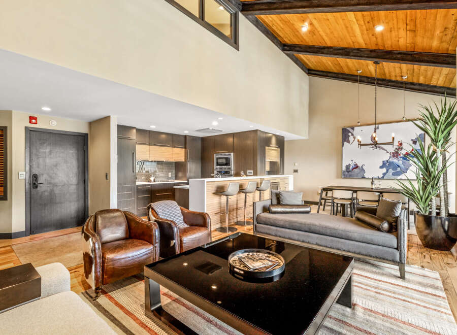 Experience modern living in this stunning open-concept space featuring a sleek kitchen with a breakfast bar, a spacious living area with vaulted ceilings and exposed beams, and a separate dining area perfect for entertaining.