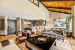 Experience modern living in this stunning open-concept space featuring a sleek kitchen with a breakfast bar, a spacious living area with vaulted ceilings and exposed beams, and a separate dining area perfect for entertaining.
