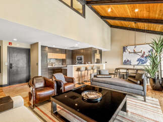 Experience modern living in this stunning open-concept space featuring a sleek kitchen with a breakfast bar, a spacious living area with vaulted ceilings and exposed beams, and a separate dining area perfect for entertaining.