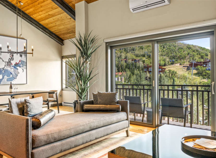Experience luxurious mountain living with this stunning living room featuring a plush chaise lounge and elegant dining area.
