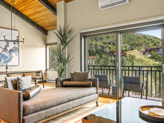 Experience luxurious mountain living with this stunning living room featuring a plush chaise lounge and elegant dining area.