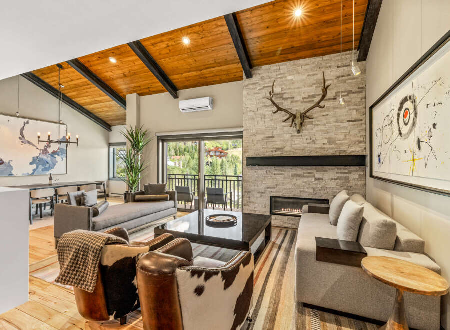 Experience luxury mountain living in this stunning great room, featuring a vaulted wood-beamed ceiling and a striking stone fireplace.