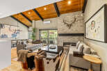 Experience luxury mountain living in this stunning great room, featuring a vaulted wood-beamed ceiling and a striking stone fireplace.