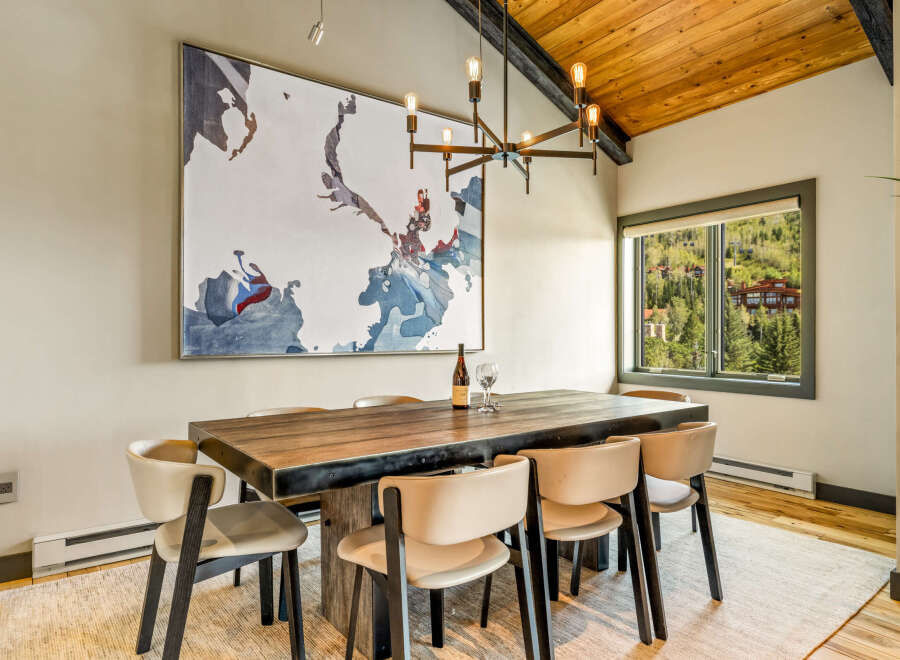 Experience elegant dining in this spacious room, featuring a large wooden table with seating for six and a striking abstract map artwork.