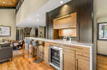 Experience luxury living with this stunning modern wet bar, featuring sleek cabinetry and a built-in wine cooler.