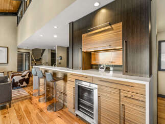 Experience luxury living with this stunning modern wet bar, featuring sleek cabinetry and a built-in wine cooler.