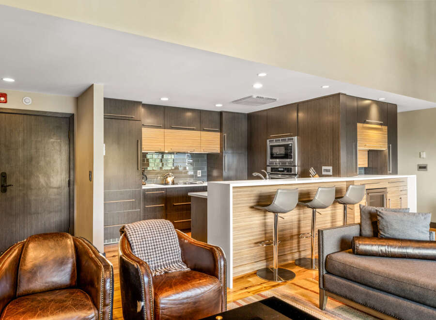Experience modern living in this stunning open-concept space, featuring a sleek kitchen with dark wood cabinetry and a chic breakfast bar perfect for entertaining.