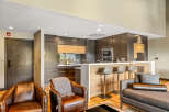 Experience modern living in this stunning open-concept space, featuring a sleek kitchen with dark wood cabinetry and a chic breakfast bar perfect for entertaining.