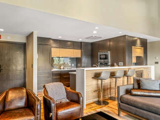 Experience modern living in this stunning open-concept space, featuring a sleek kitchen with dark wood cabinetry and a chic breakfast bar perfect for entertaining.