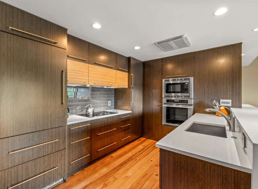 Experience modern elegance in this stunning kitchen, featuring sleek, dark wood cabinetry with integrated rose gold hardware.