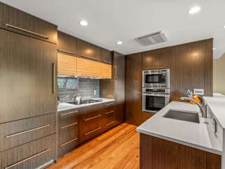 Experience modern elegance in this stunning kitchen, featuring sleek, dark wood cabinetry with integrated rose gold hardware.