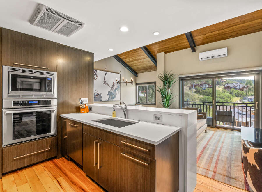 Experience modern living in this stunning kitchen featuring sleek, dark wood cabinetry and a built-in stainless steel oven and microwave.