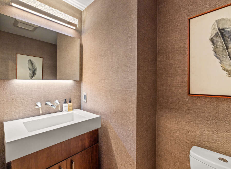 This powder room features a modern white vessel sink atop a dark wood vanity, complemented by sleek chrome fixtures.
