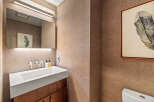 This powder room features a modern white vessel sink atop a dark wood vanity, complemented by sleek chrome fixtures.